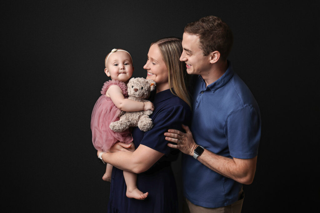 family portrait mother and father family photography navy blue backdrop natural lighting candid photo